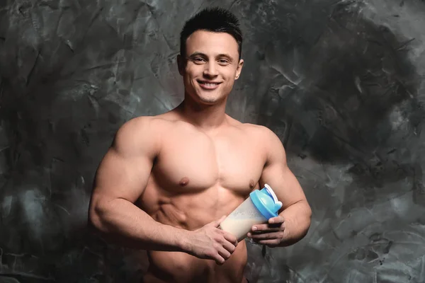 Sportlicher Mann mit Proteinshake auf Grunge-Hintergrund — Stockfoto