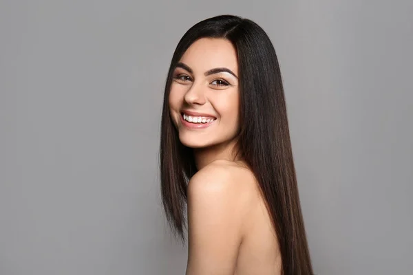 Portrait of beautiful young woman with healthy long hair on grey background — Stock Photo, Image