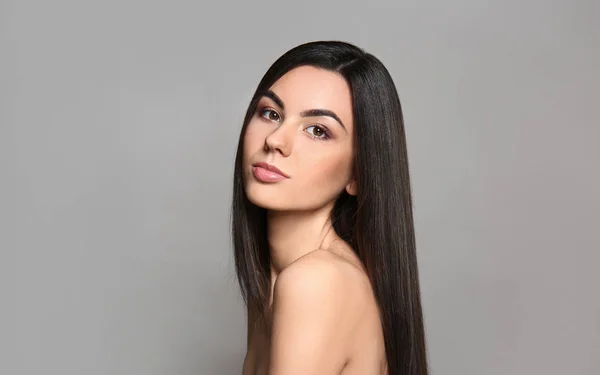 Gyönyörű fiatal nő portréja, hosszú hajú, szürke háttérrel — Stock Fotó