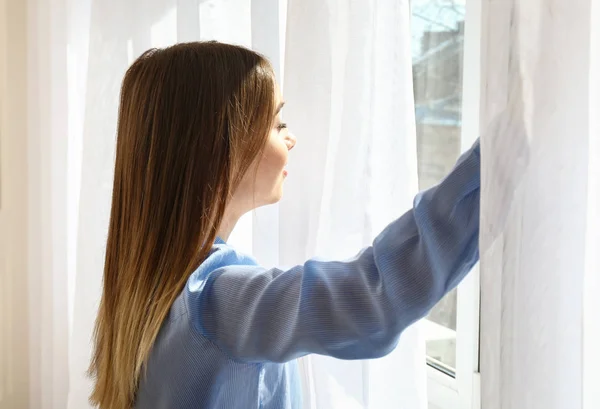 Jonge vrouw het openen van licht gordijnen thuis — Stockfoto