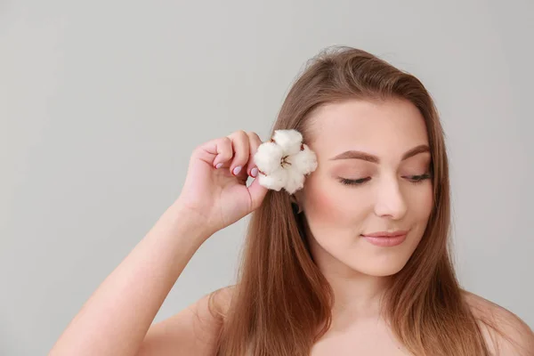Krásná mladá žena s bavlněnou květinou na pozadí — Stock fotografie