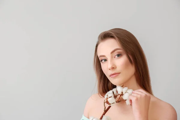 Vacker ung kvinna med bomulls gren på ljus bakgrund — Stockfoto