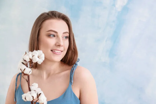 Vacker ung kvinna med bomull gren på färg bakgrund — Stockfoto
