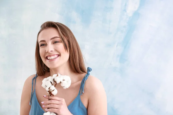 Vacker ung kvinna med bomull gren på färg bakgrund — Stockfoto