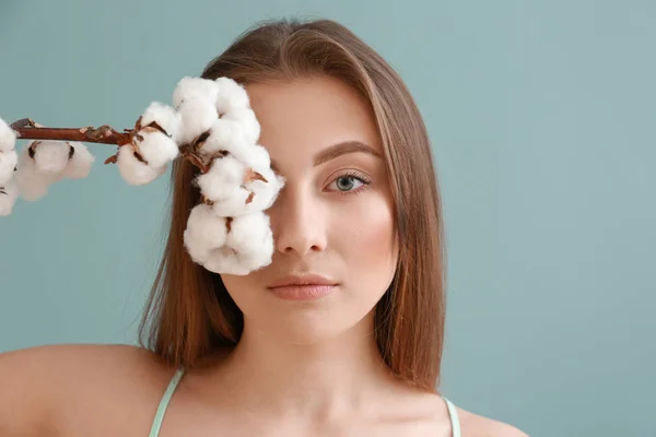 Beautiful young woman with cotton branch on color background — Stock Photo, Image