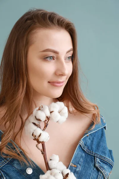 Beautiful young woman with cotton branch on color background — Stock Photo, Image