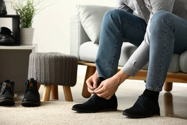 Jonge man zetten op schoenen in de kamer — Stockfoto