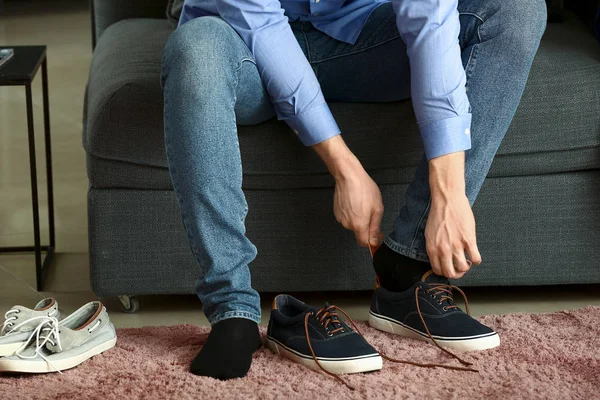 Hombre joven poniéndose zapatos en la habitación — Foto de Stock