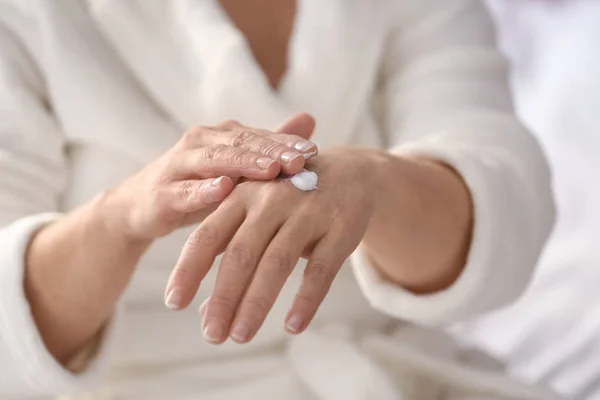 Mature woman applying hand cream at home, closeup — Stock Photo, Image