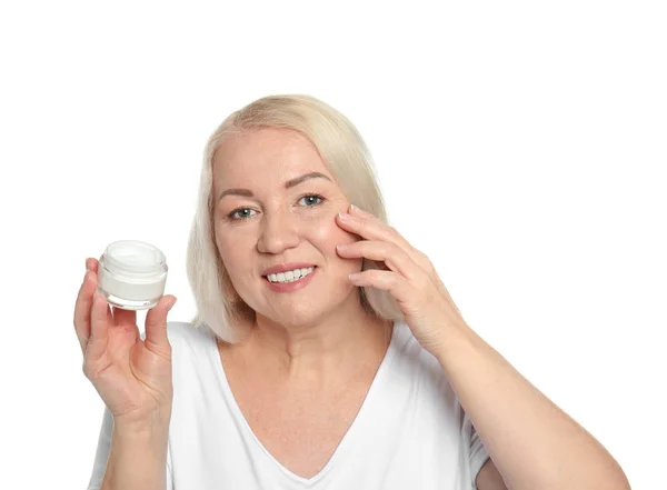 Mulher madura aplicando creme facial no fundo branco — Fotografia de Stock