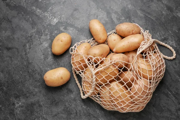 Saitentasche mit rohen Kartoffeln auf grauem Hintergrund — Stockfoto
