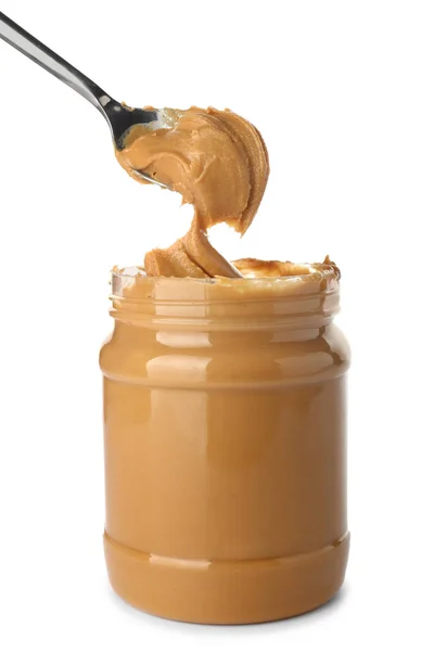 Tomando de manteiga de amendoim saborosa do jarro no fundo branco — Fotografia de Stock