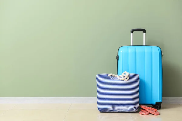 Packed suitcase and beach bag near color wall — Stock Photo, Image