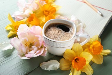 Ahşap arka planda kahve, güzel çiçekler ve Notebook fincan