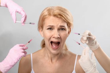 Hafif arka planda yaşlanma karşıtı enjeksiyonları için şırıngalar tutan Olgun kadın ve eller çığlık