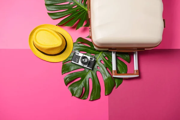 Suitcase, tropical leaves, photo camera and hat on color background. Travel concept — Stock Photo, Image