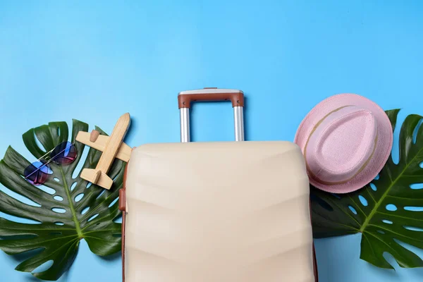 Valise, feuilles tropicales, chapeau et avion jouet sur fond de couleur. Concept de voyage — Photo