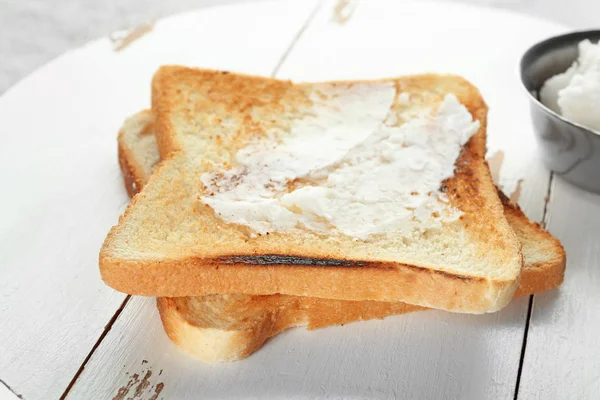 Tasty toasted bread with coconut oil on wooden board