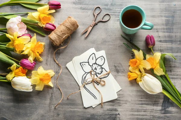 Bukett av vackra blommor, kort, kopp kaffe, sax och tråd på grått bord — Stockfoto