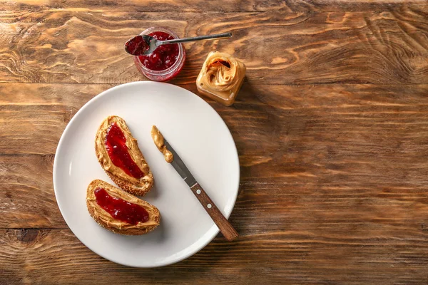 Ahşap masada lezzetli fıstık ezmesi ve reçel ile ekmek — Stok fotoğraf