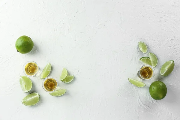 Composition with shots of tequila and lime on white background — Stock Photo, Image