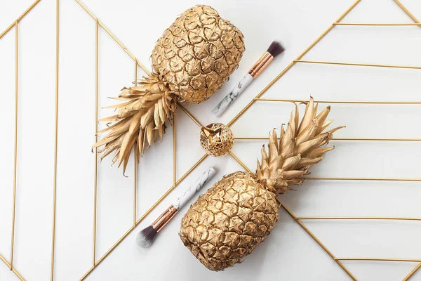 Composition with golden pineapples and makeup brushes on white background — Stock Photo, Image