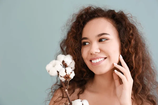 Beautiful young woman with cotton branch on color background — Stock Photo, Image