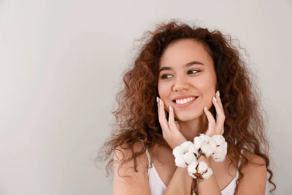 Mulher bonita com ramo de algodão no fundo claro — Fotografia de Stock