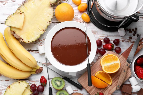 テーブルの上においしいチョコレートフォンデュと果物とボウル — ストック写真