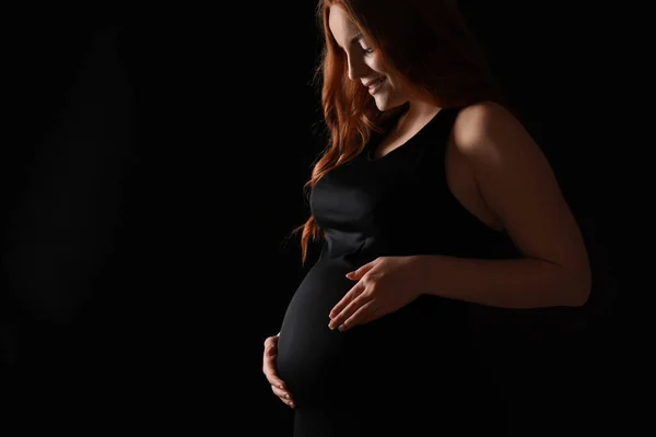 Vakker, gravid kvinne med mørk bakgrunn – stockfoto