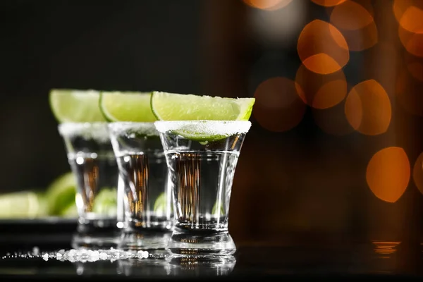 Tomas de tequila en la mesa contra luces desenfocadas —  Fotos de Stock