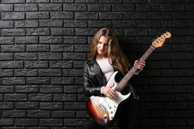 Karanlık duvara karşı gitar çalan genç kız