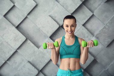 Gri duvara karşı dambılile sportif kadın eğitimi