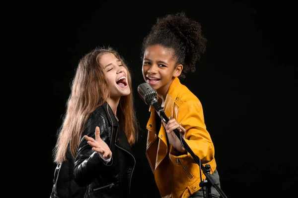 Adolescentes com microfone cantando contra fundo escuro — Fotografia de Stock