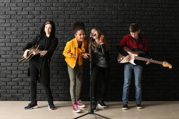 Banda de músicos adolescentes tocando contra a parede escura — Fotografia de Stock