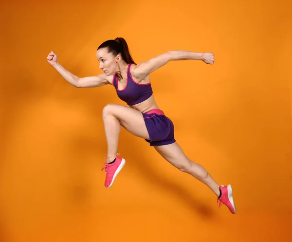 Спортивная бегущая женщина на цветном фоне — стоковое фото