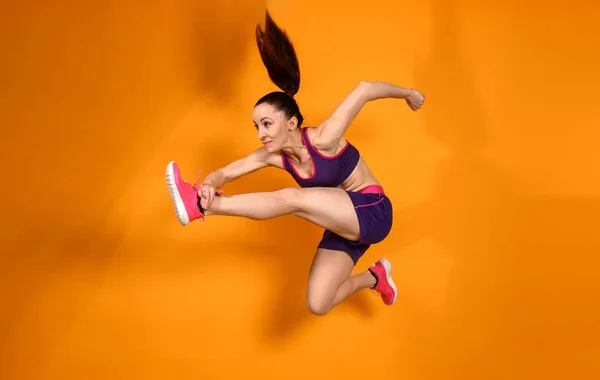 Спортивные прыжки женщина на цветном фоне — стоковое фото