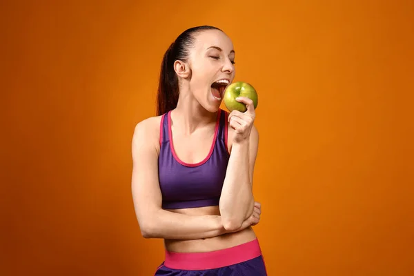 运动的女人吃苹果的颜色背景 — 图库照片