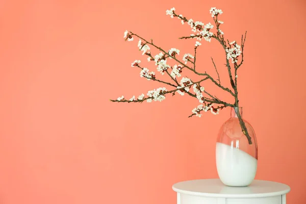 Ваза з красивими квітучими гілками на столі на кольоровому фоні — стокове фото