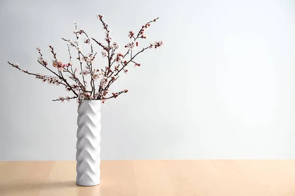 明るい背景を背景にテーブルの上に美しい花の枝を持つ花瓶 — ストック写真