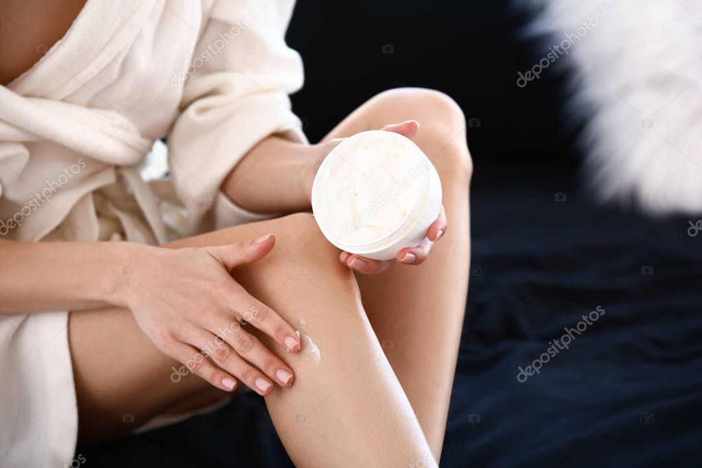 Beautiful young woman applying cream after epilation at home, closeup