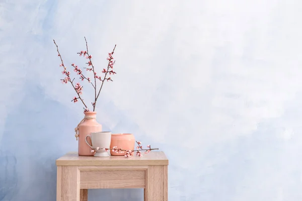 美しい開花の枝、キャンドルとテーブルの上にカップと花瓶 — ストック写真