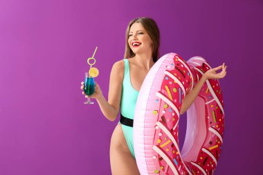 Renkli arka planda şişme yüzük ve kokteyl ile güzel genç kadın