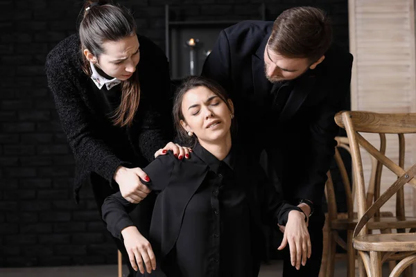 Relatives calming young widow at funeral — Stock Photo, Image