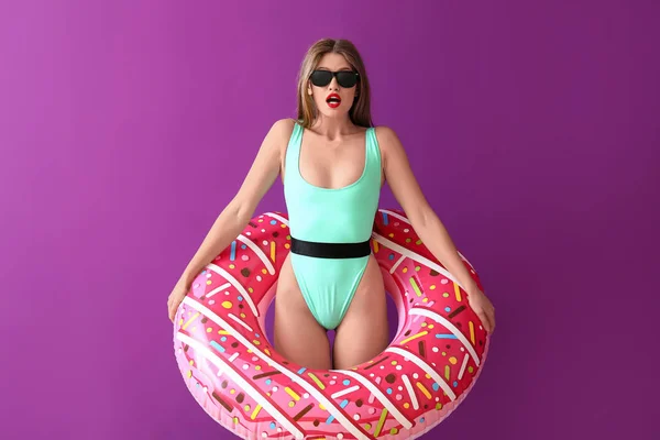 Überraschte junge Frau mit aufblasbarem Ring auf farbigem Hintergrund — Stockfoto