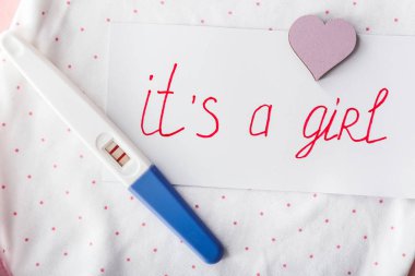 Metin li kağıt Bir Kız ve bebek kıyafetleri üzerinde gebelik testi