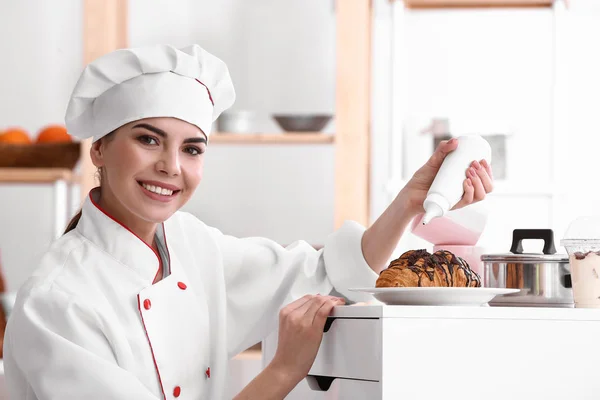 Junge Konditorin dekoriert Croissants in der Küche — Stockfoto