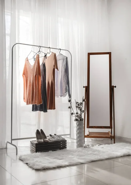 Big mirror with female clothes in interior of room