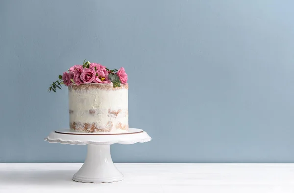 甜蛋糕与花卉装饰在桌子上的颜色背景 — 图库照片