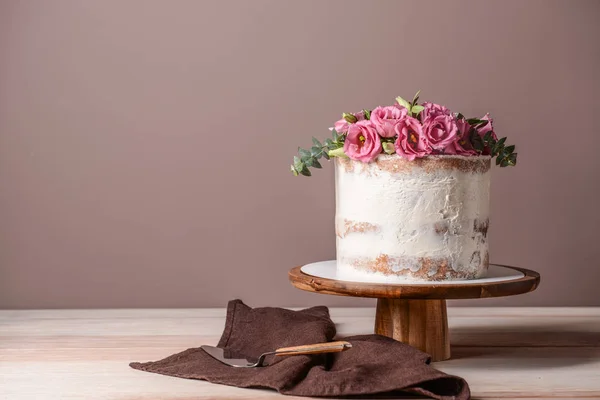 Sweet cake with floral decor on table against color background — Stock Photo, Image